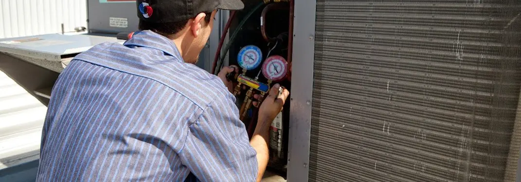 HVAC technician servicing a condenser unit in Speedway