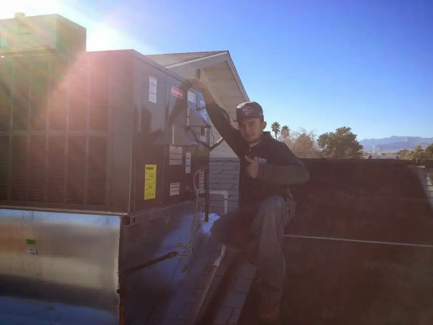 HVAC technician performing Air Duct Repair on a rooftop unit in Speedway